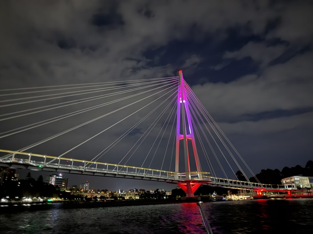 Kurilpa Bridge — a web of light and steel across the Brisbane River. It carries walkers, cyclists, and late-night wanderers