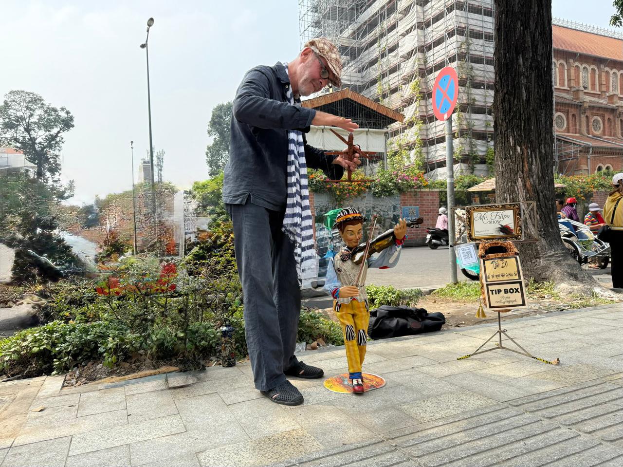 Street puppeteer Filip performing with marionette Mr. Filipo on a Saigon pavement outside the French Post Office, Ho Chi Minh City