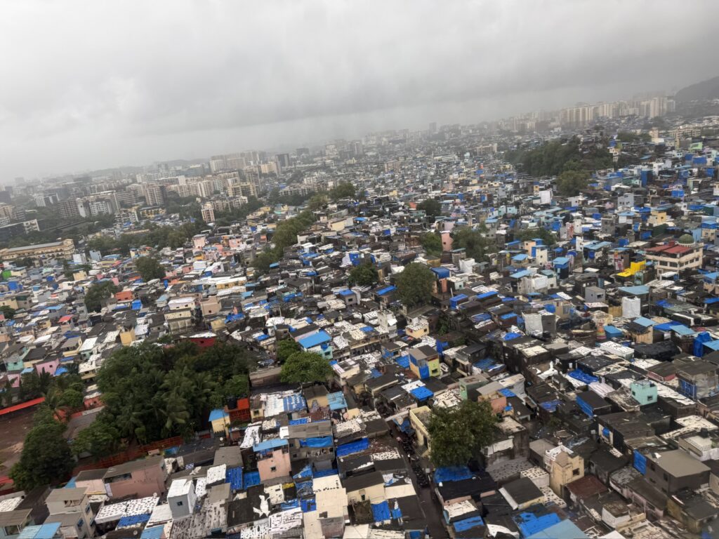 Mumbai settlements from the air in the monsoon, roofs covered in blue plastic sheets