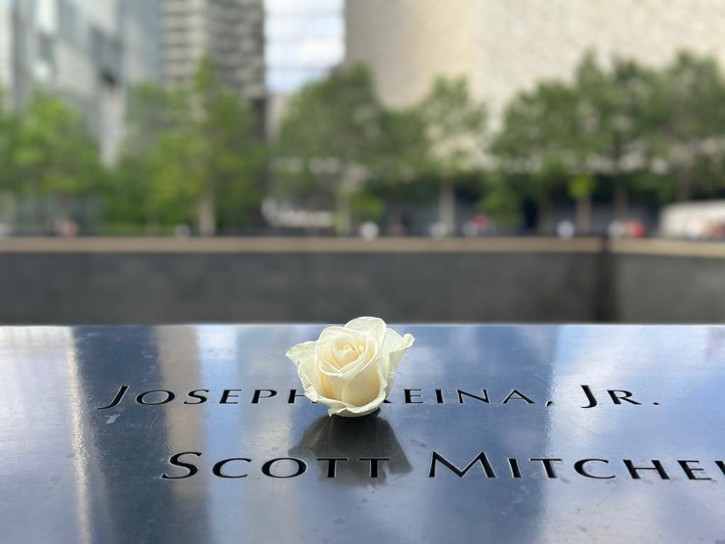 A single white rose placed in the engraved letters of a name on the bronze parapet at the 9/11 Memorial in New York
